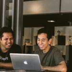 two smiling men looking at MacBook