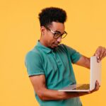 a man in a green shirt holding a laptop