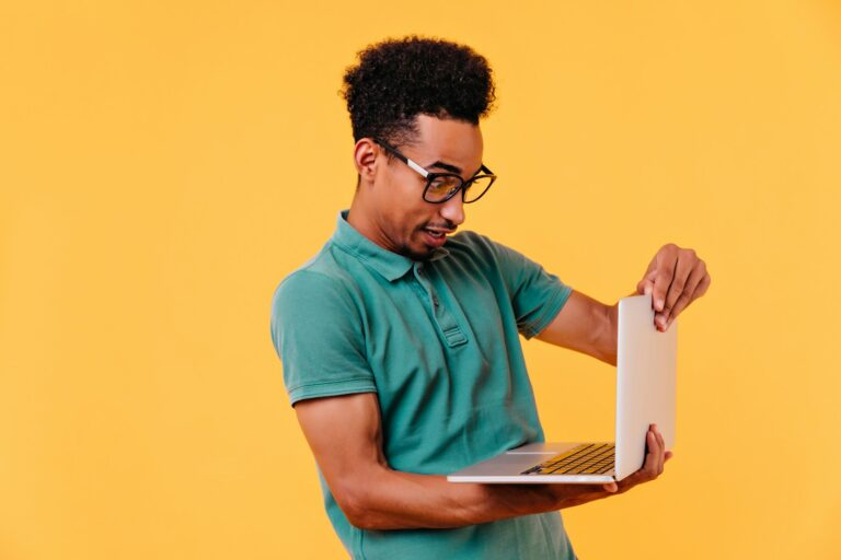 a man in a green shirt holding a laptop